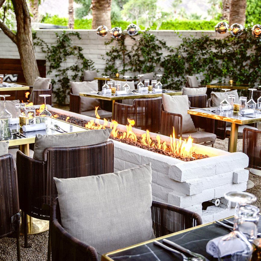 The tree-filled, firelit patio of SOPA, Hermann Bungalow's on-site fine dining restaurant in Palm Springs.