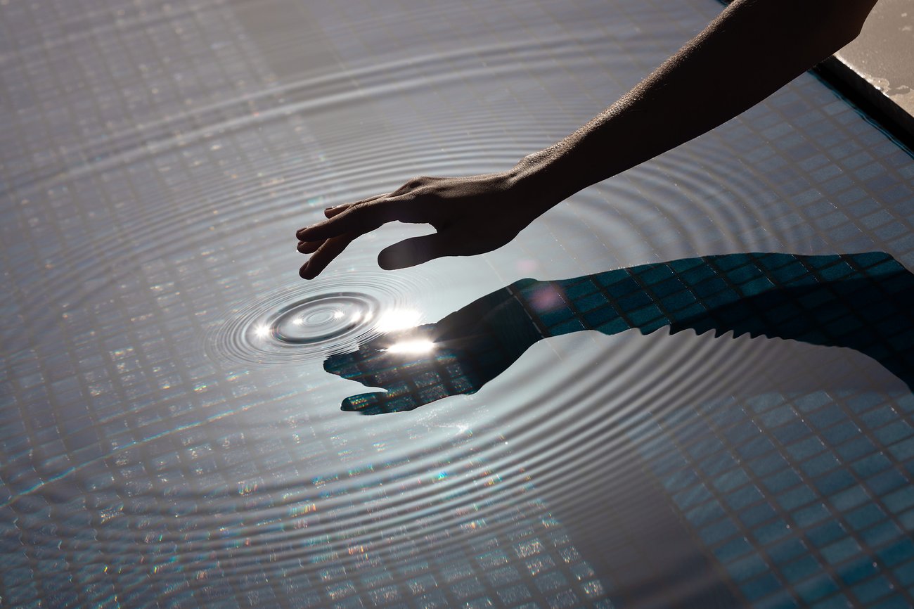 A hand creating ripples in the pool under the California sun at our Palm Springs retreat.