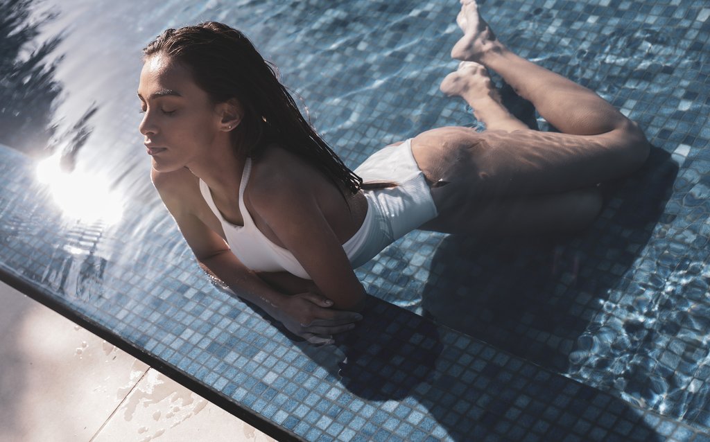 Woman lying in the pool on the tiles