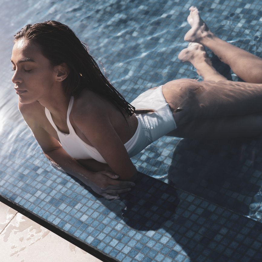 Woman lying in the pool on the tiles