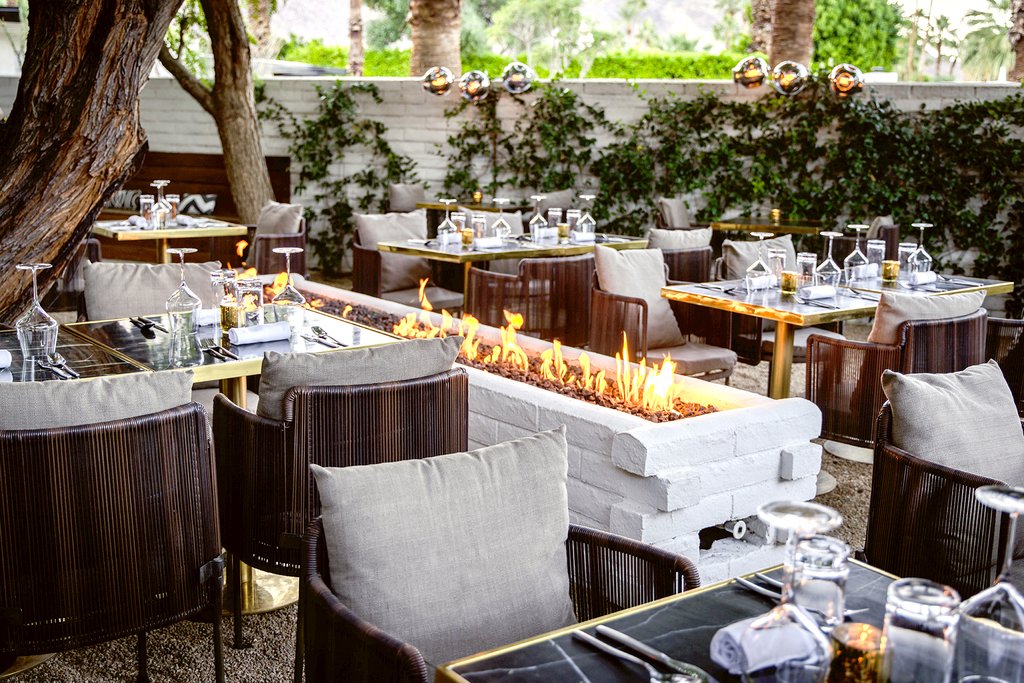 The tree-filled, firelit patio of SOPA, Hermann Bungalow's on-site fine dining restaurant in Palm Springs.